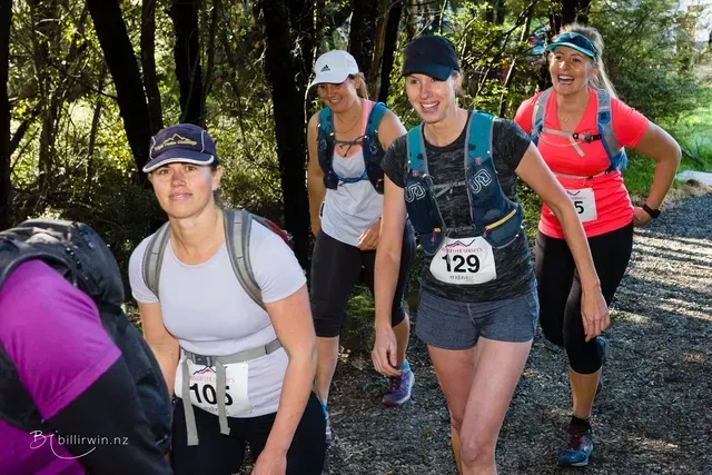 A group of women are walking down a path in the woods.