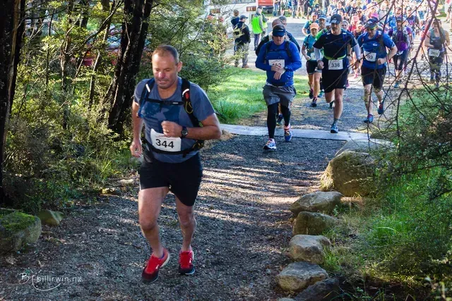 A group of people are running down a path in the woods.