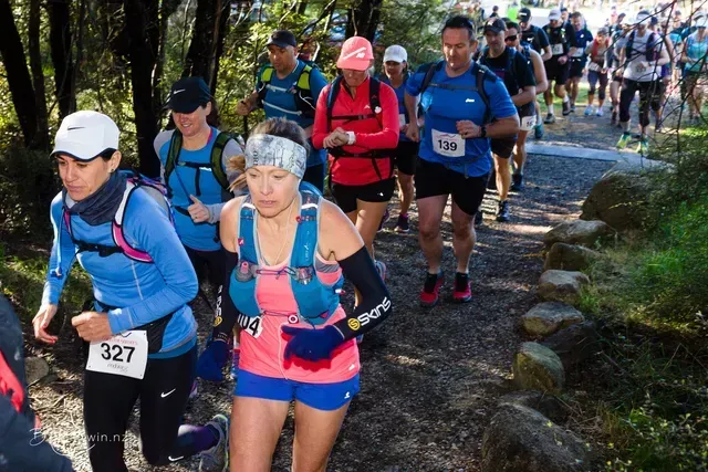 A group of people are running on a trail in the woods.