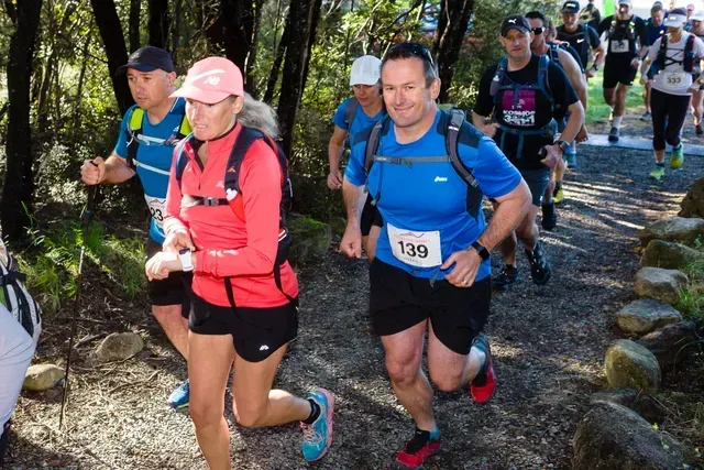 A group of people are running on a trail and one of them has the number 139 on his shirt