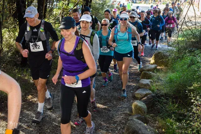A group of people are running down a trail.