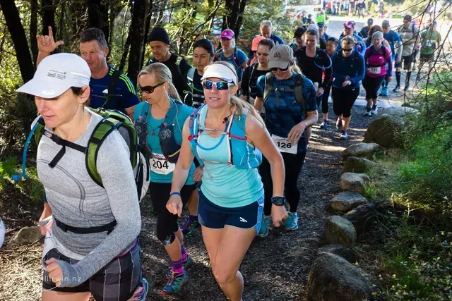 A group of people are walking down a path in the woods.