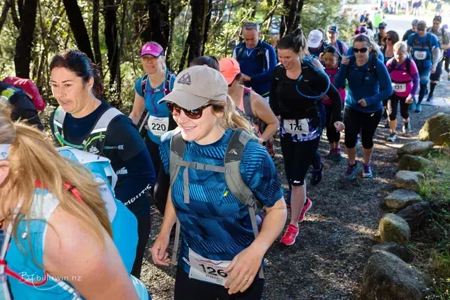 A group of people are walking down a path in the woods.
