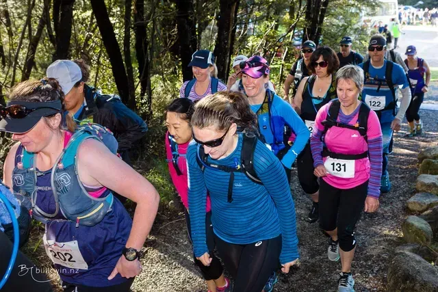 A group of people are walking down a path in the woods.