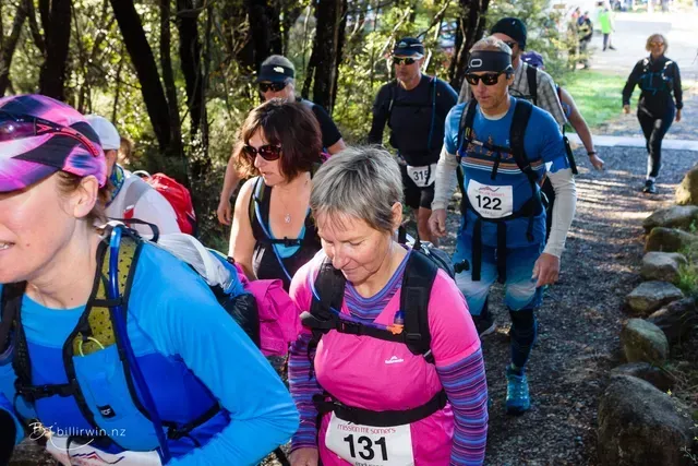 A group of people are walking down a path in the woods.