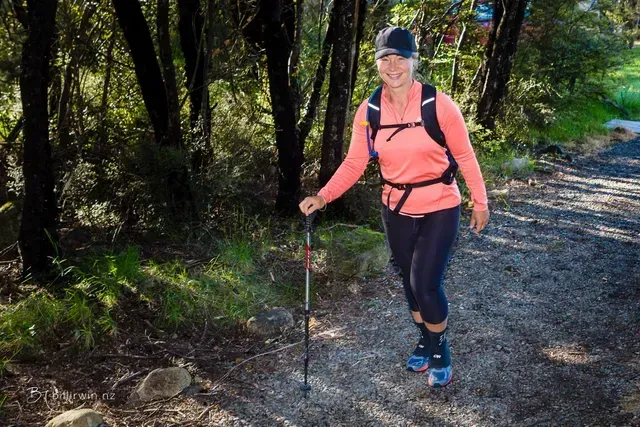 A woman is walking down a dirt path in the woods.