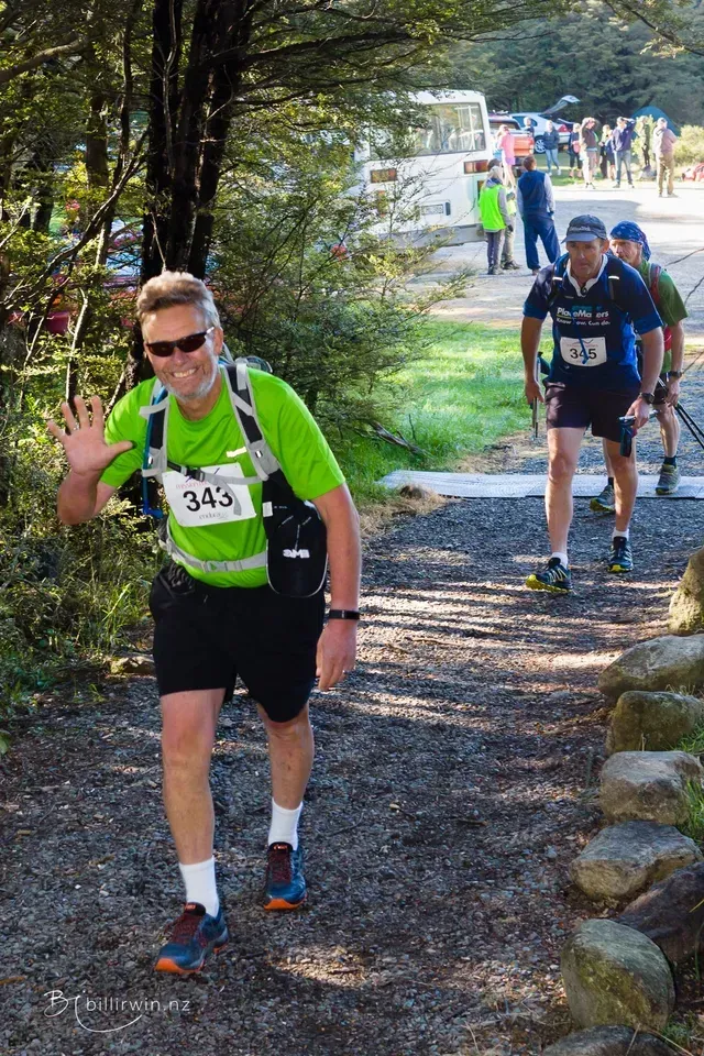A man in a green shirt is walking down a dirt path.