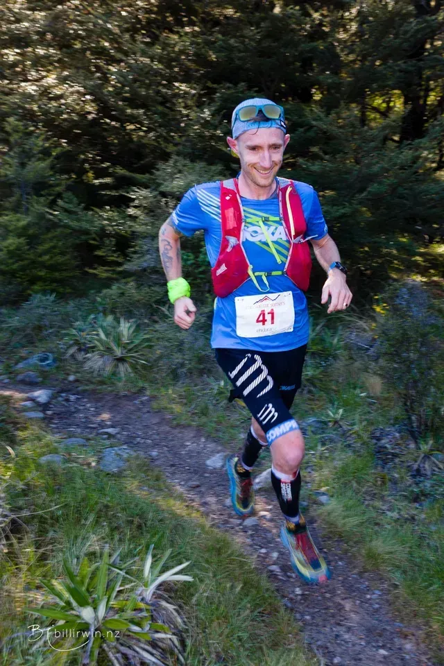 A man is running on a trail in the woods.