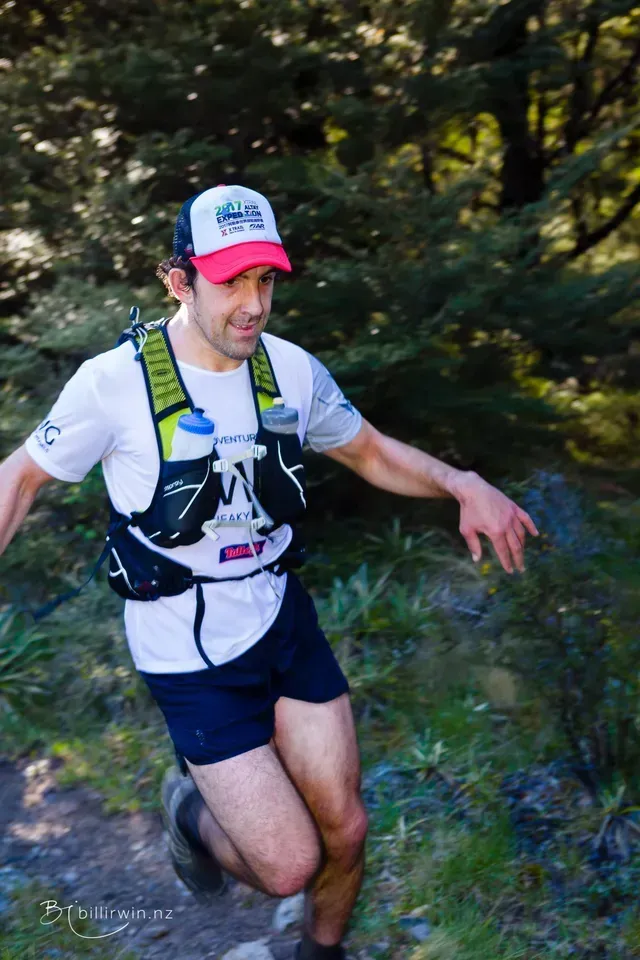 A man is running down a trail in the woods.