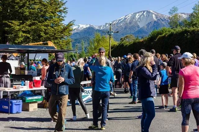 A group of people are walking down a street with mountains in the background.