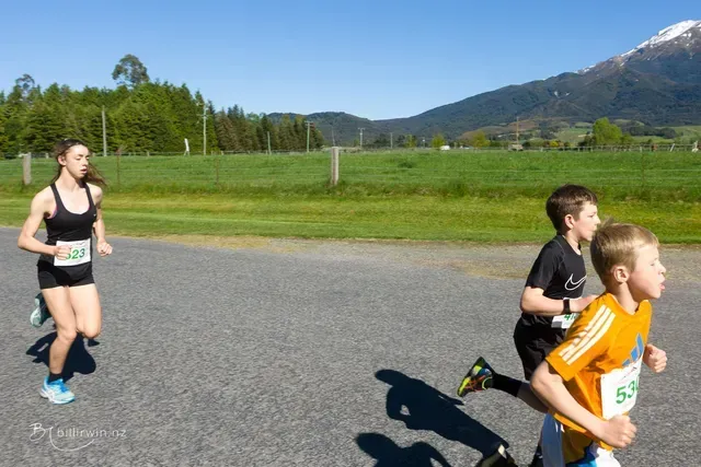 A group of people are running on a road with mountains in the background.