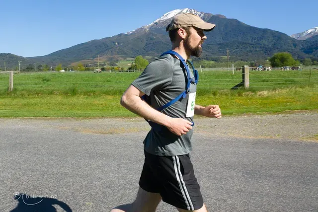 A man is running on a road with a mountain in the background