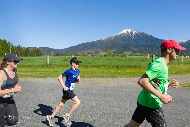 A group of people are running on a road with mountains in the background.