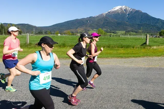 A group of women are running on a road with a mountain in the background