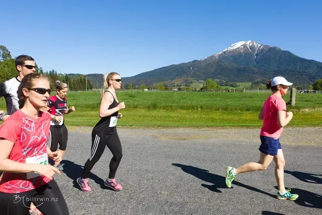 A group of people are running on a road with a mountain in the background.