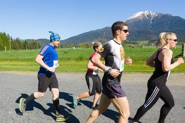 A group of people are running on a road with mountains in the background.