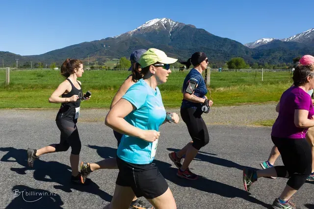A group of women are running on a road with mountains in the background
