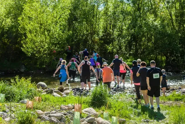 A group of people are walking across a river.