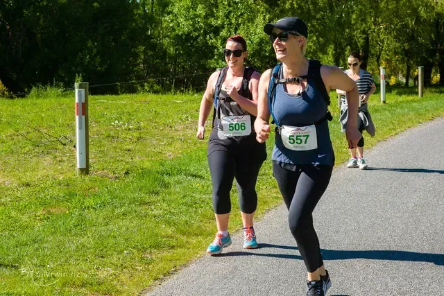 Two women are running on a path in a park.