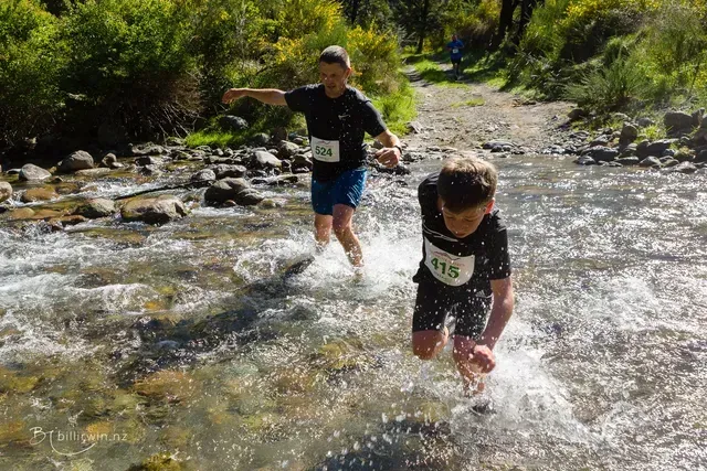 Two young boys are running through a river.
