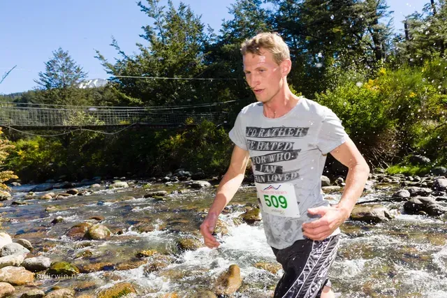 A man wearing a number 509 shirt is running through a stream