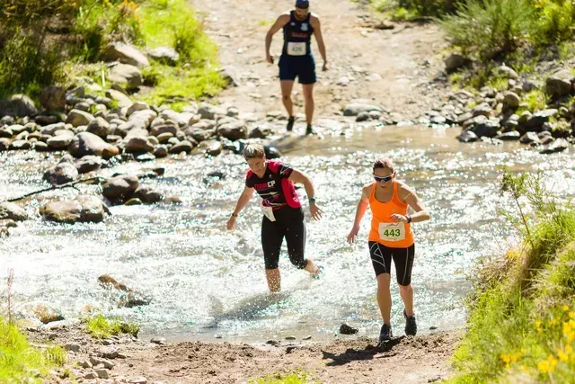 A group of people are running through a river.