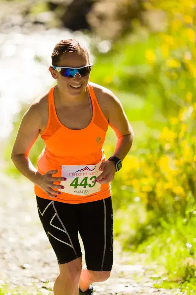 A woman is running in a race with the number 443 on her shirt.