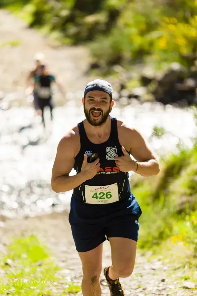 A man is running down a trail next to a river.