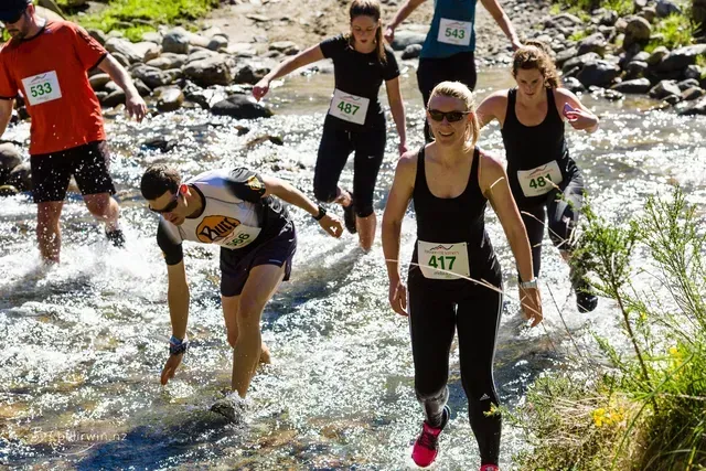 A group of people are running through a river.
