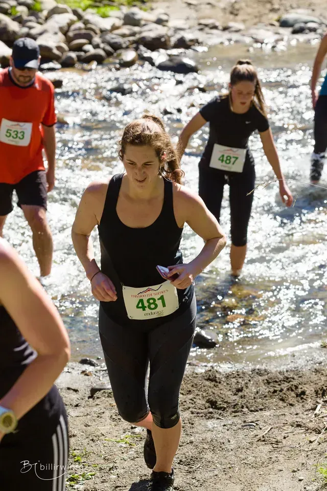 A group of people are running through a river.