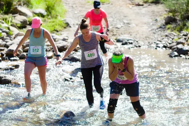 A group of people are running through a river.