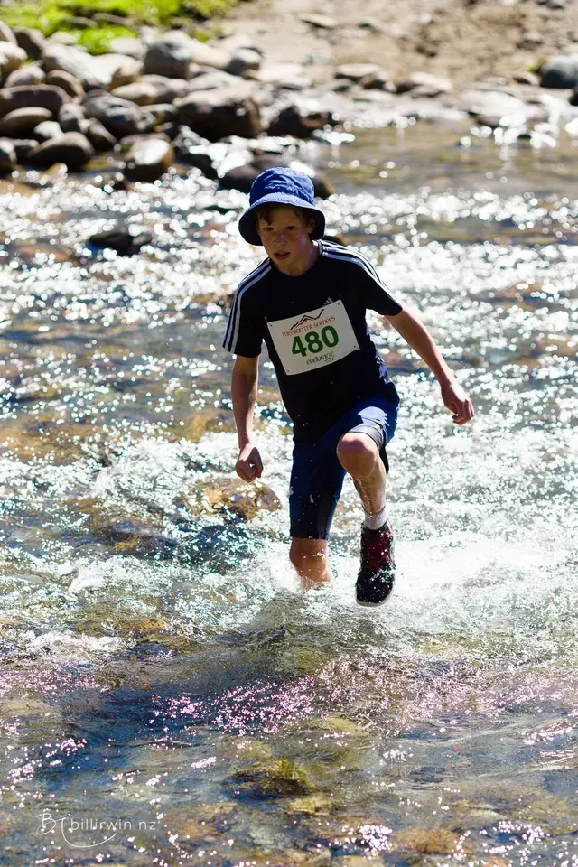 A young boy is running through a river.