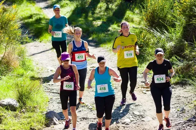 A group of women are running down a dirt path.