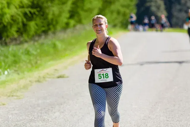 A woman is running in a race on a road.