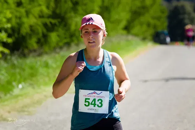 A woman is running in a race with the number 543 on her shirt.