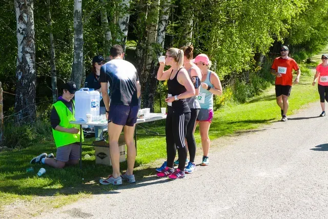 A group of people are standing around a table drinking water.