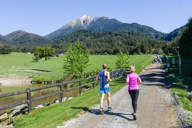 A man and a woman are running down a dirt road.