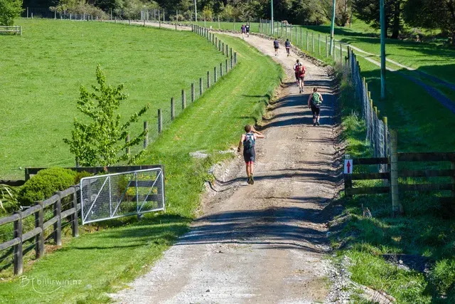 A group of people are walking down a dirt road.