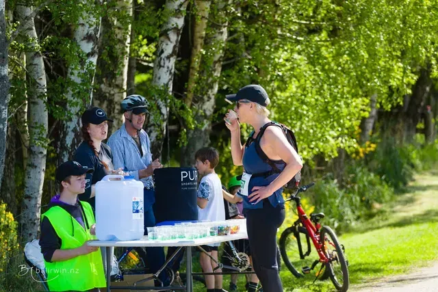 A group of people are standing around a table in the woods.