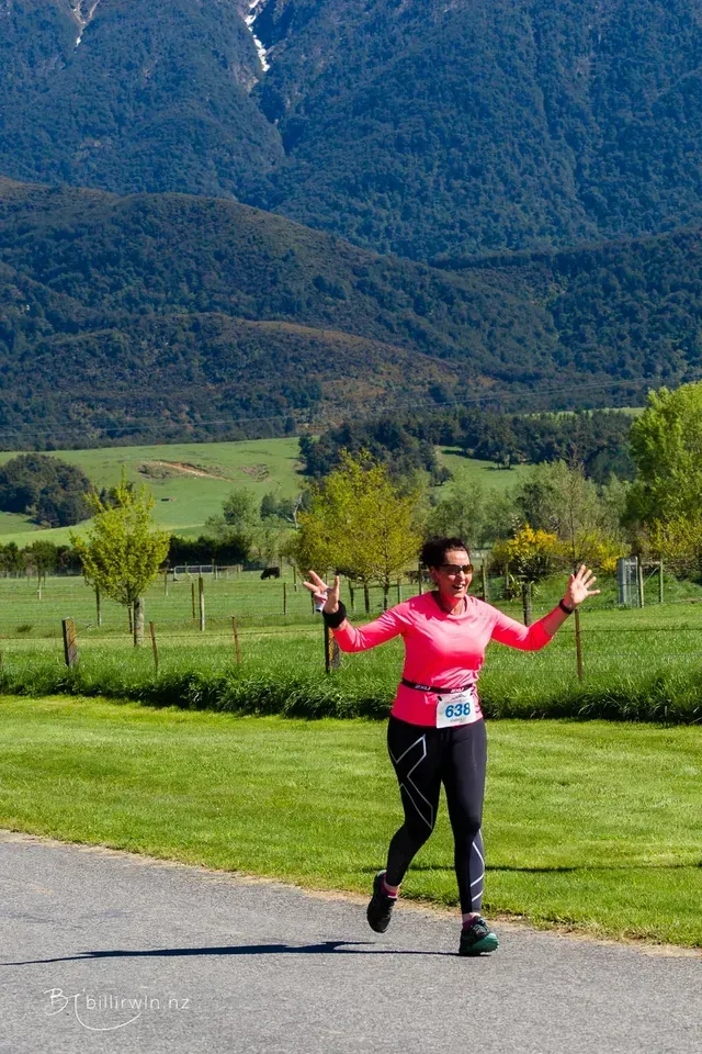 A woman is running down a road with her arms outstretched.