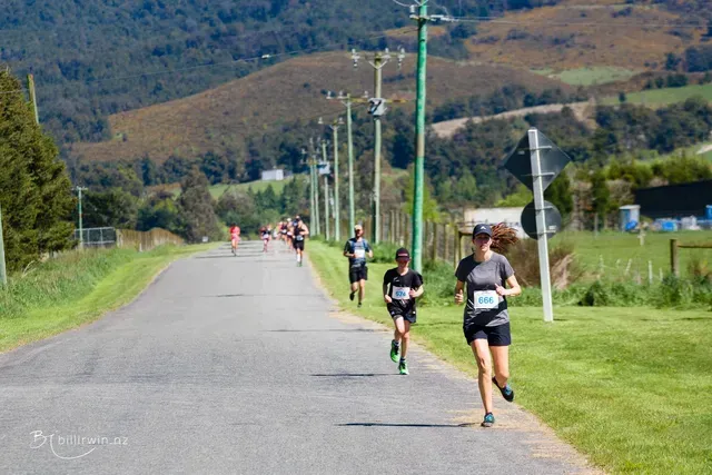 A group of people are running down a road.