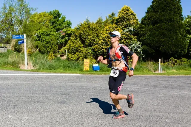 A person is running down a road with a number on their bib.