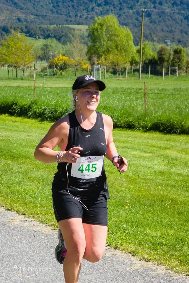 A woman is running a marathon on a road.