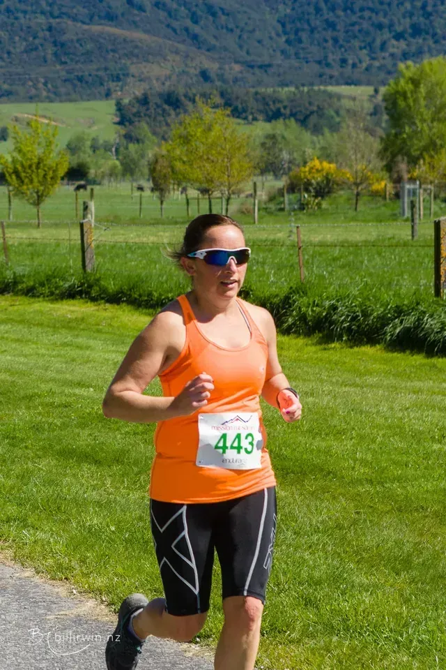 A woman is running in a race with the number 443 on her shirt.