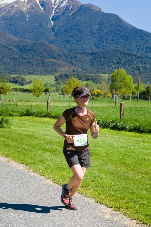 A woman is running on a path with mountains in the background.