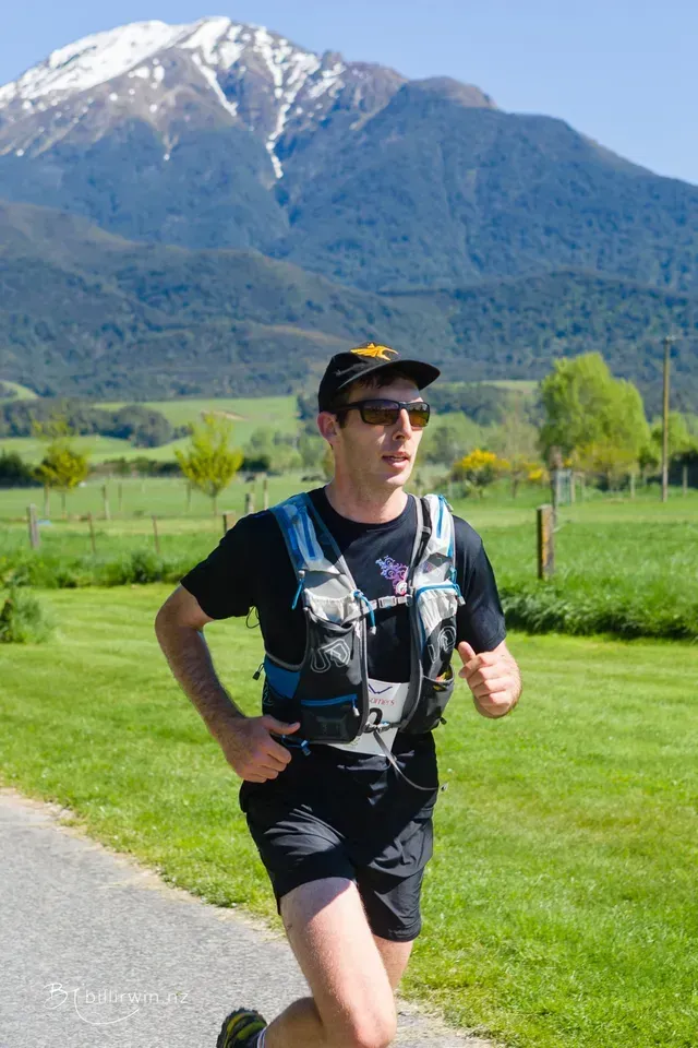 A man is running on a path with a mountain in the background.