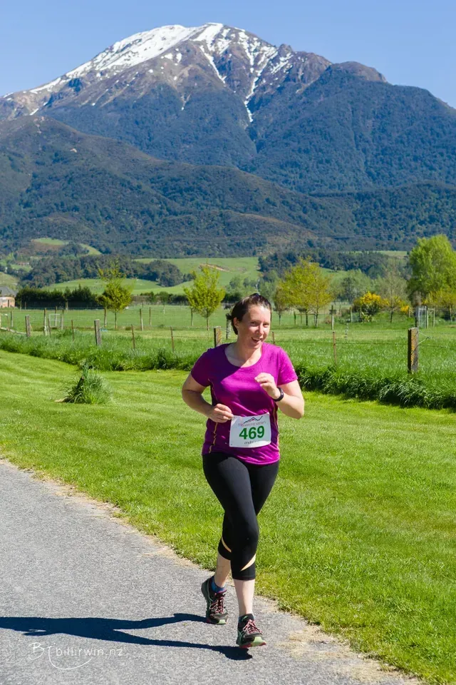 A woman is running on a path with a mountain in the background.