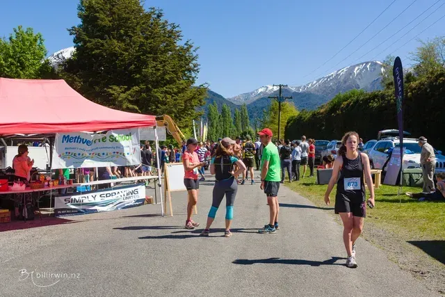 A group of people are walking down a street with mountains in the background.