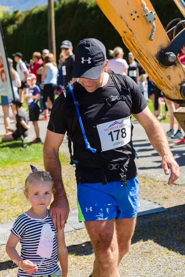 A man with the number 178 on his shirt is walking with a little girl.