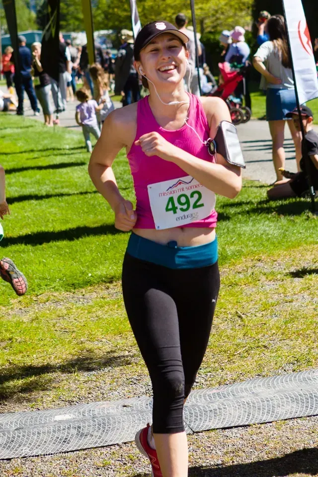 A woman is running in a race with the number 492 on her shirt.